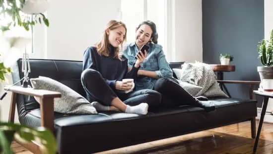 Zwei junge Frauen sitzen auf einer Couch
