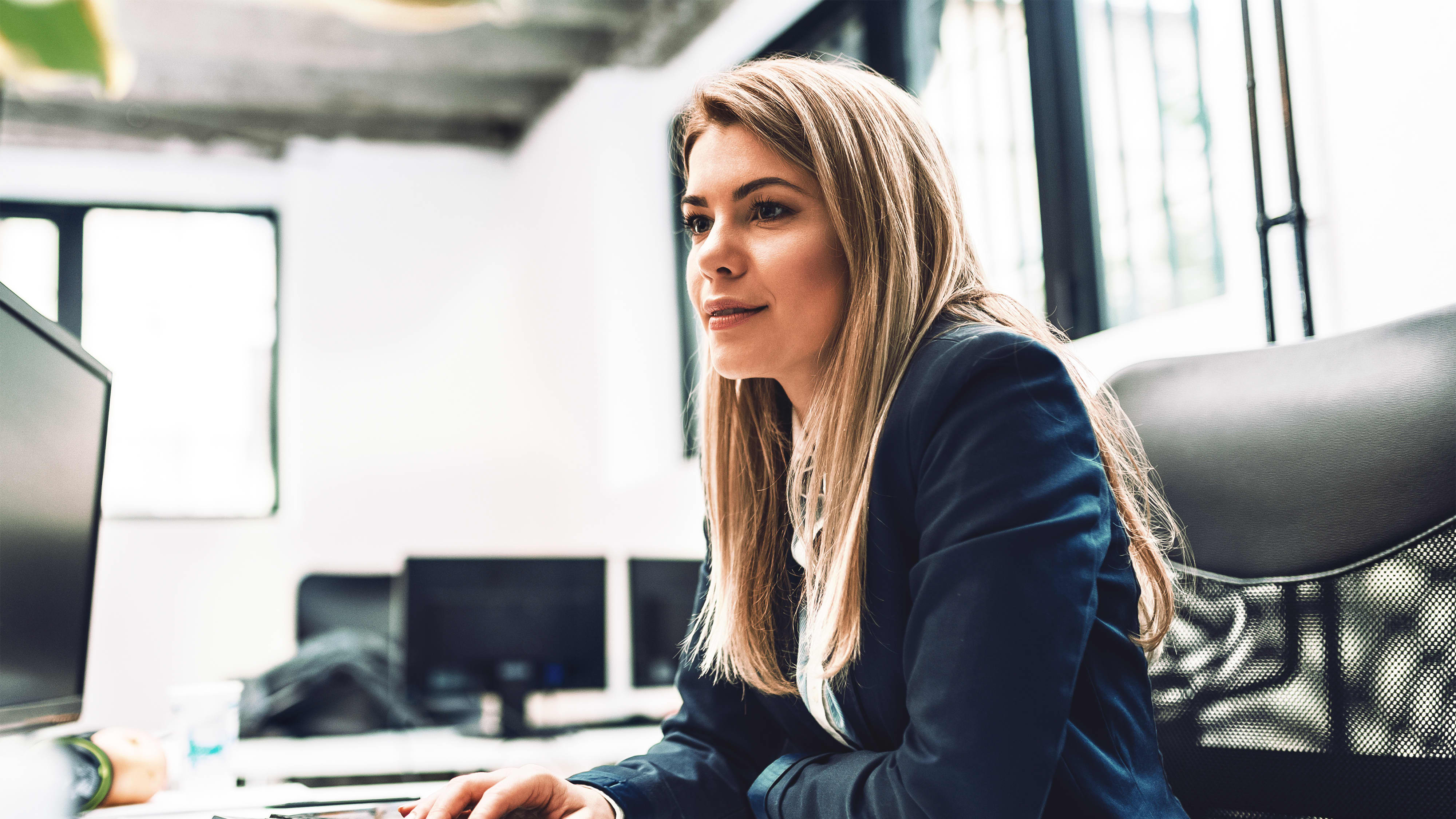 Titelbild für Infoseite “MBA - Salesforce”: Vertriebsleiterin arbeitet am Schreibtisch im Büro