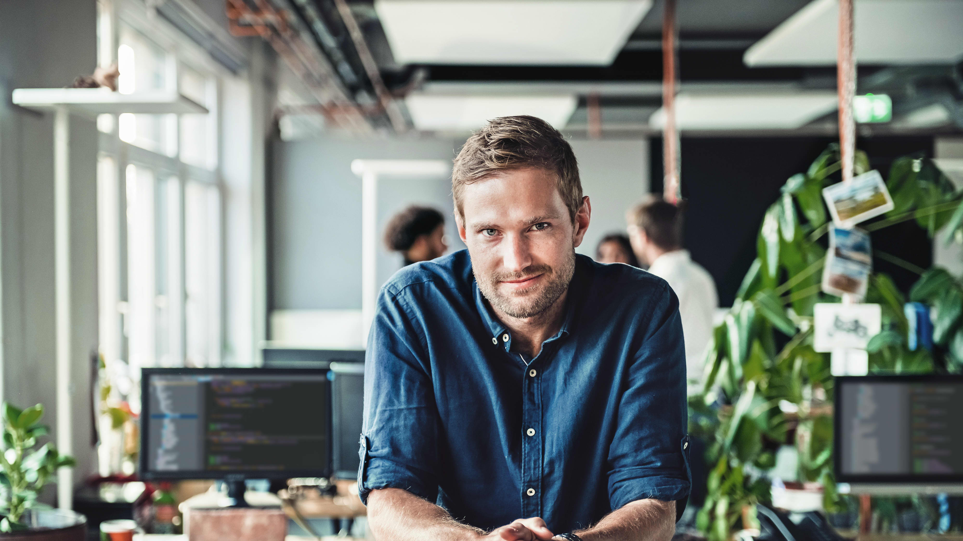 Titelbild für Infoseite “Master DevOps and Cloud Computing”: DevOps Engineer arbeitet am Schreibtisch im Büro