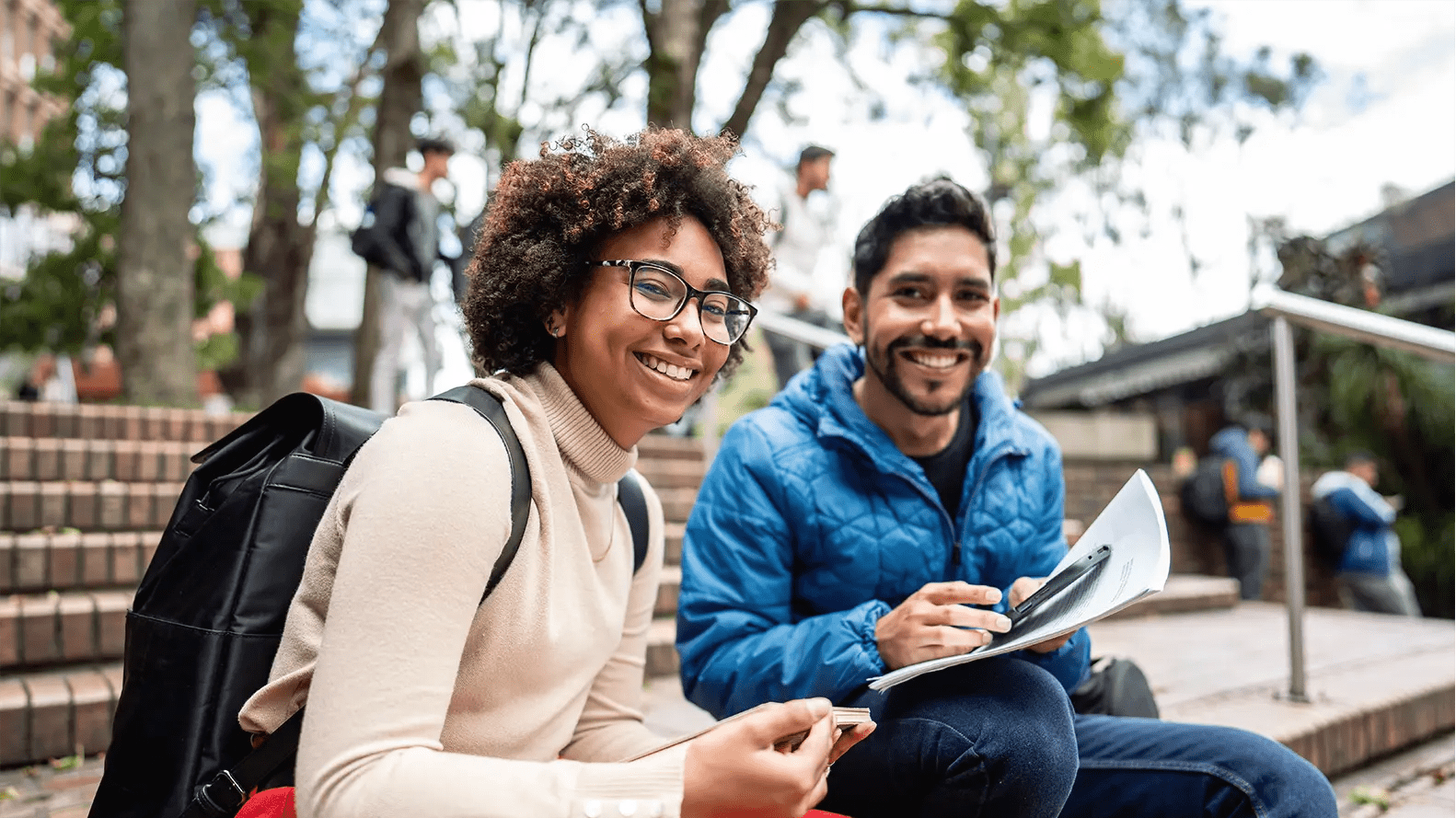 Titelbild zur Infoseite "Studium und Ausbildung": Zwei Studierende sitzen draußen am Campus
