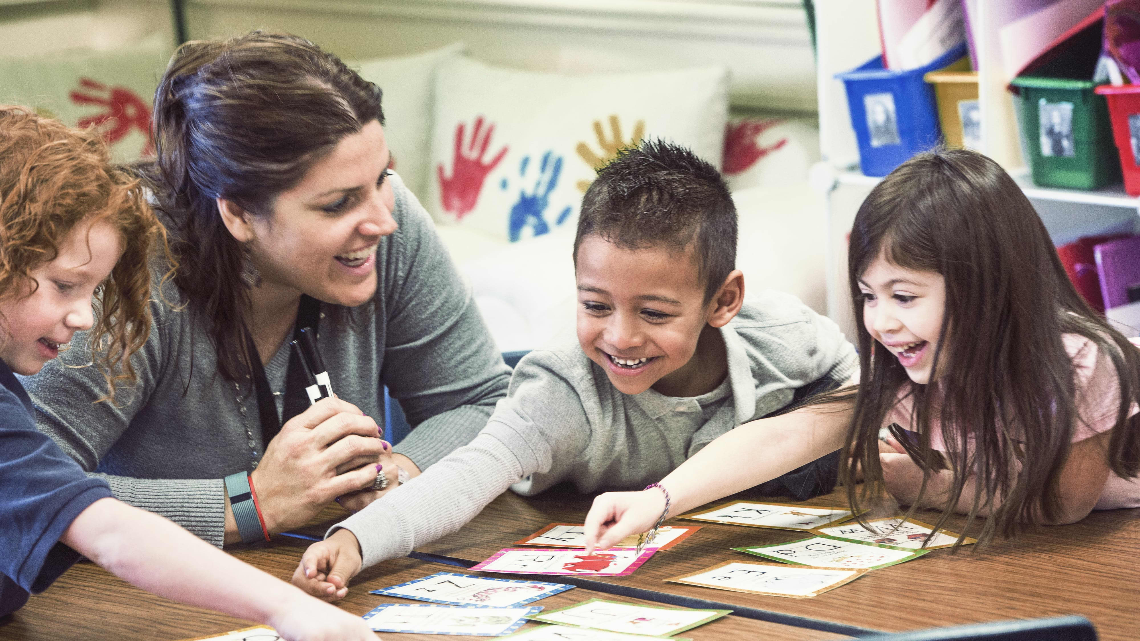 A teacher smiling at her students at a school working on arts and crafts