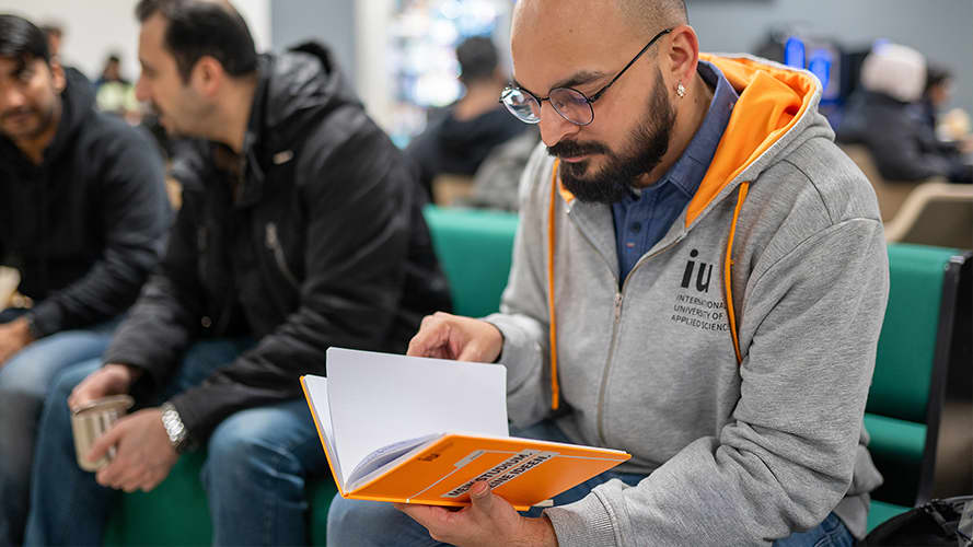IU student wearing a branded IU hoodie and reading an agenda