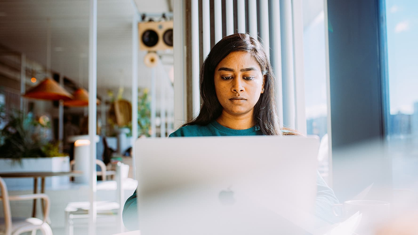 An International student is sitting and studying with her laptop in a happening cafe in Berlin.