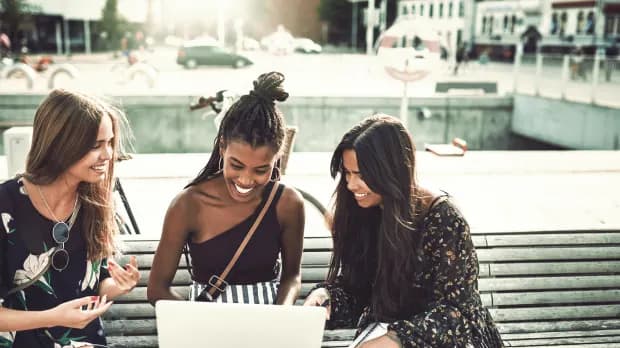 Drei junge Frauen schauen gemeinsam auf einen Laptop