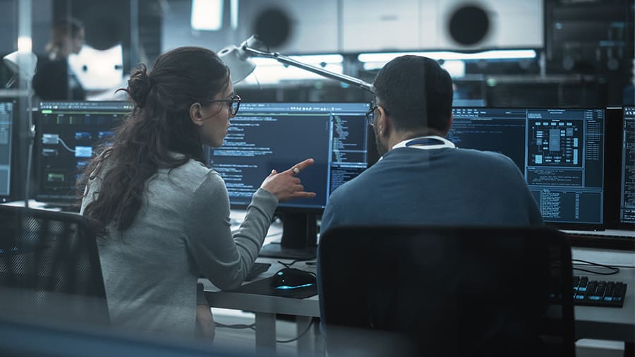 Man and woman sitting in front of their desktops talking about how to build ai models
