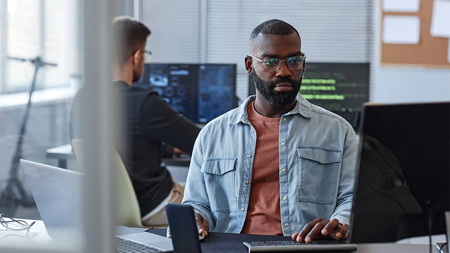 Man with glasses and a jean shirt looks focused to test machine learning models