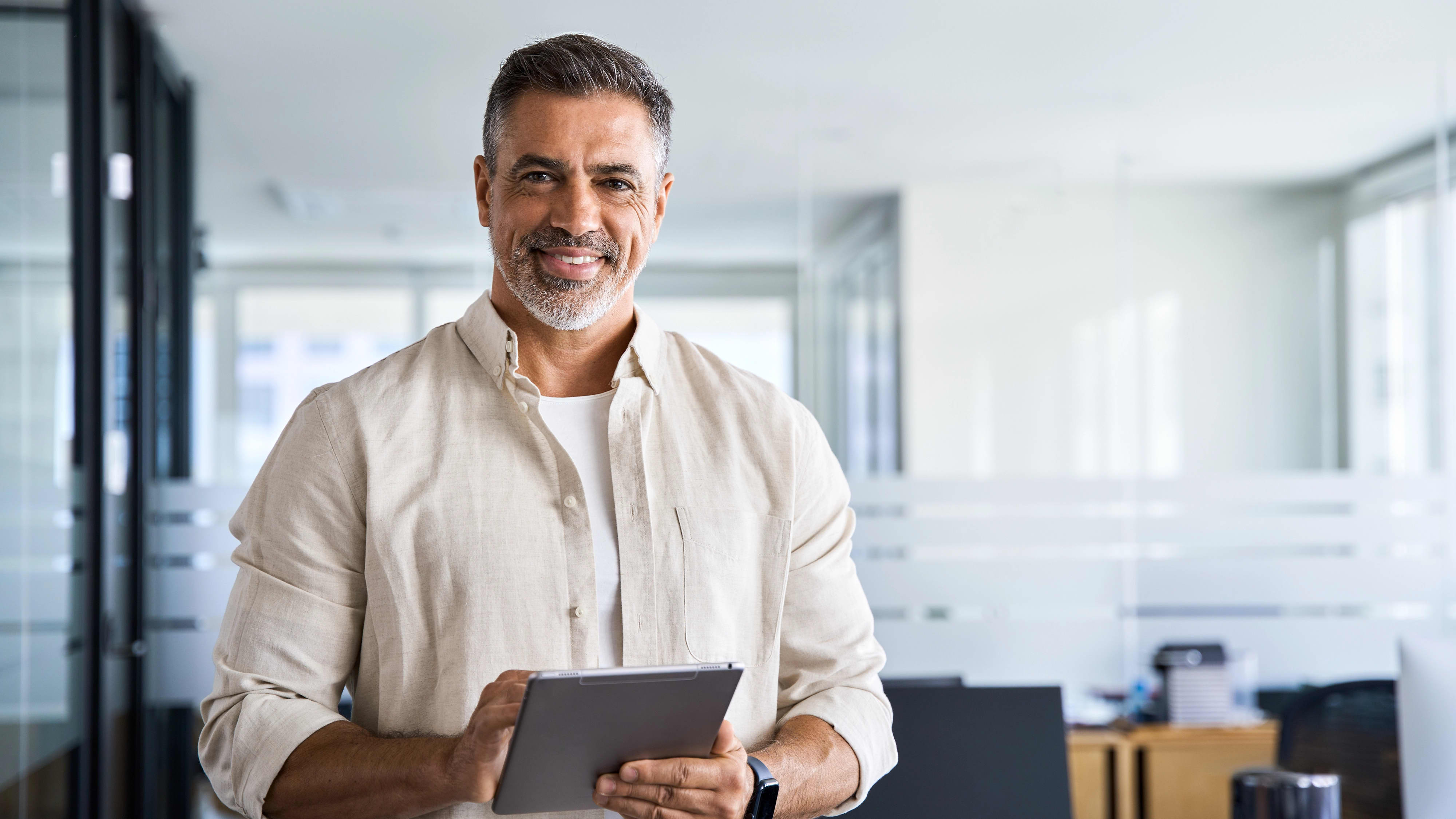 Adult man holding a tablet and smiling in an office environment