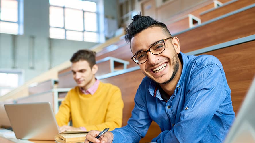 A student in a classroom smiling at the camera