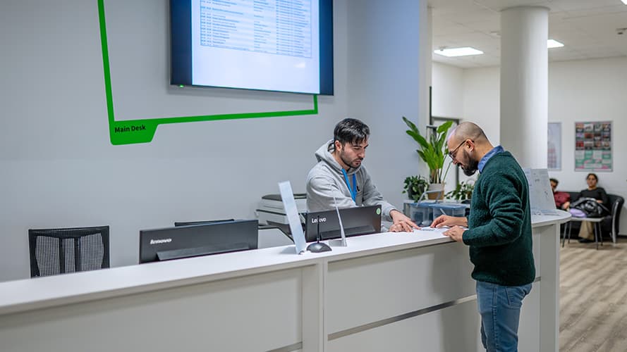 Two men talking at the IU´s main desk at the Berlin Campus