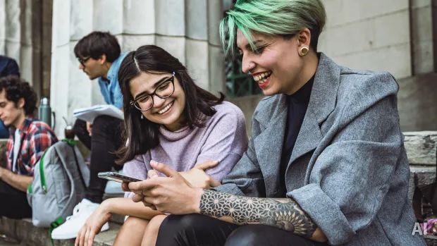 Zwei junge Frauen schauen gemeinsam auf ein Handy, AI-generated