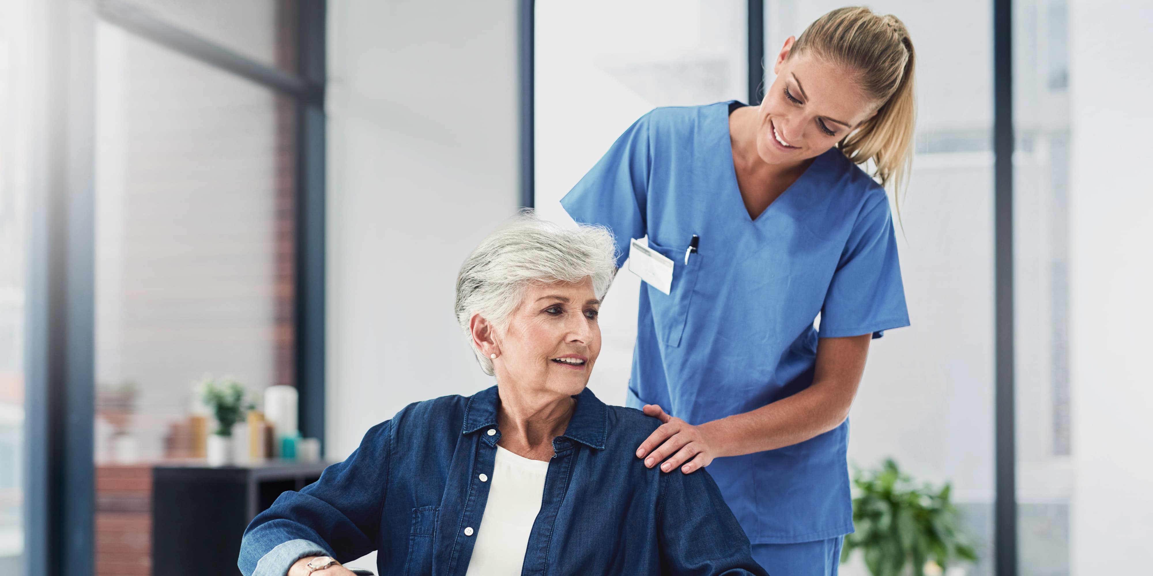 Titelbild für Infoseite “Bachelor Pflege”: Pflegerin hilft Patientin in Rollstuhl