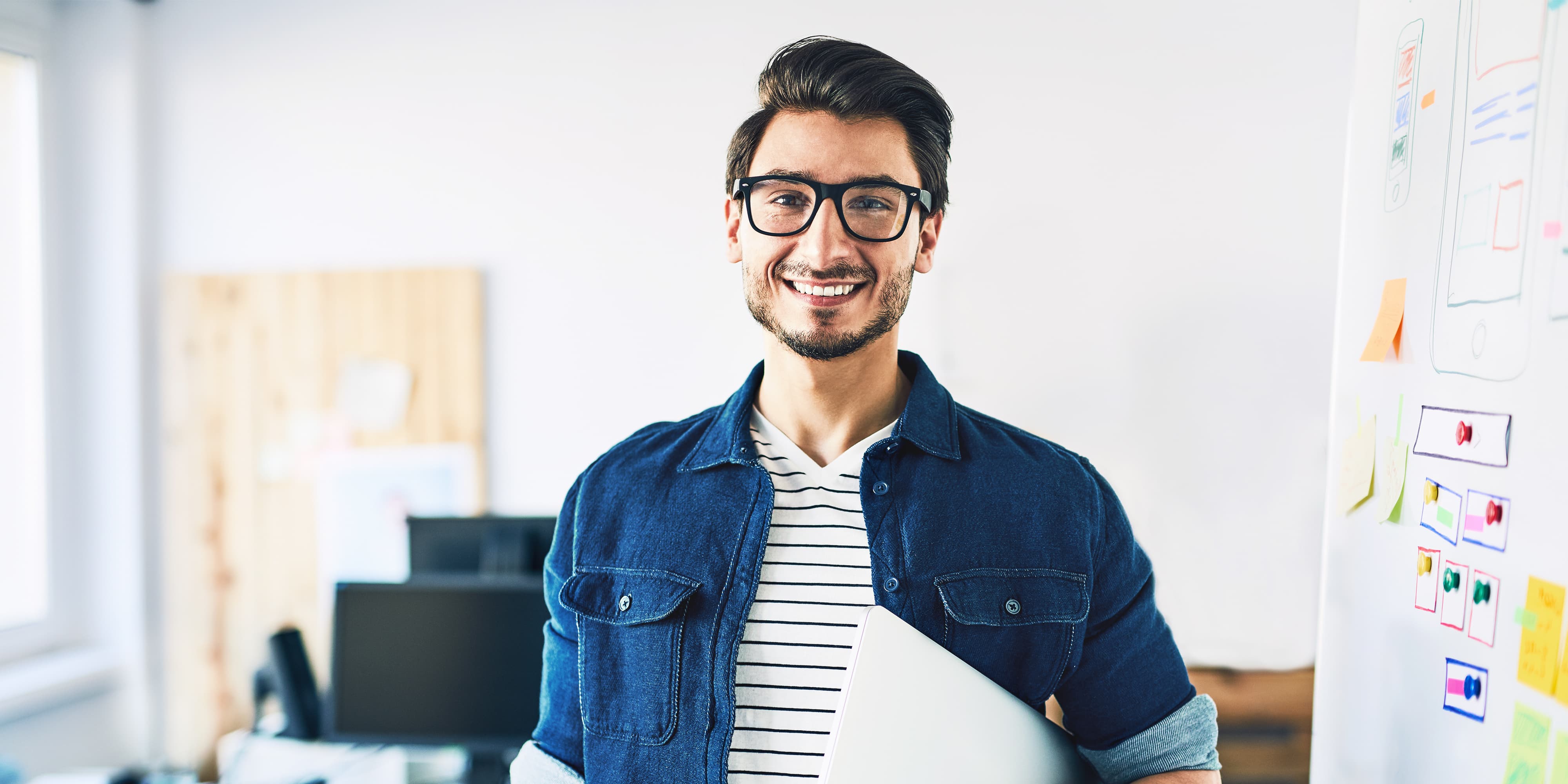 Titelbild für Infoseite “Bachelor Customer Centricity”: Student mit Laptop steht vor einem Whiteboard