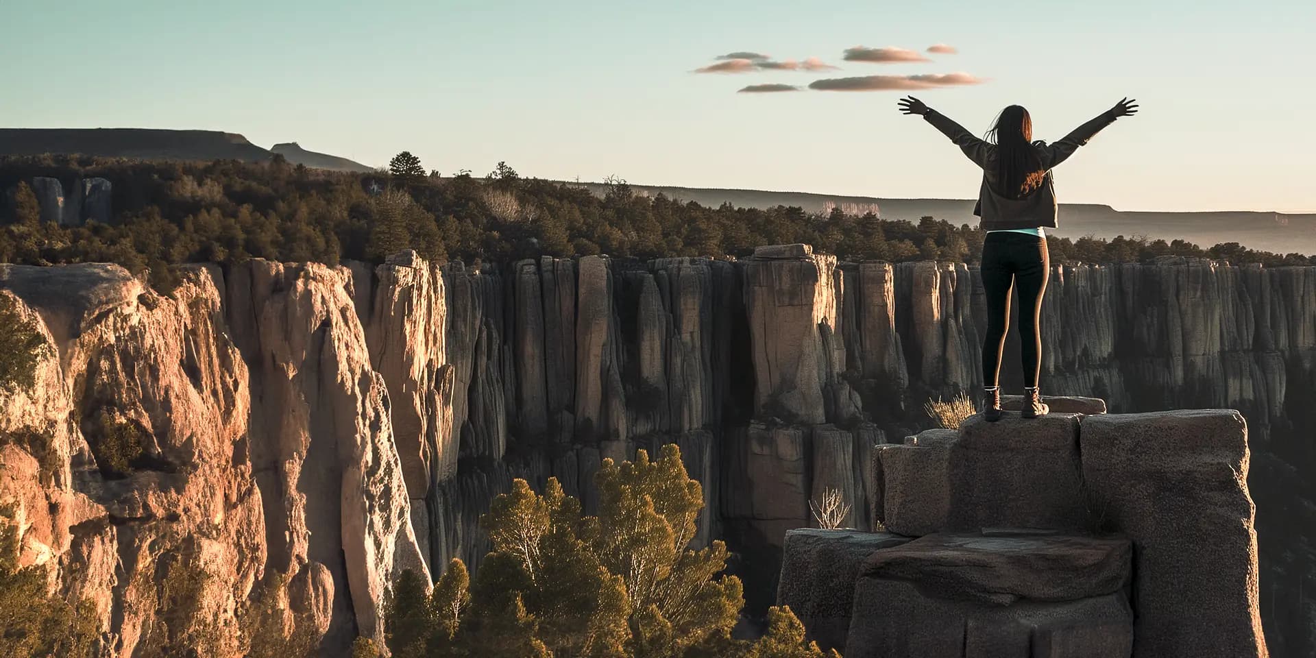 Titelbild zum Artikel "Bucket List": Studentin steht mit offen Armen am Felsen