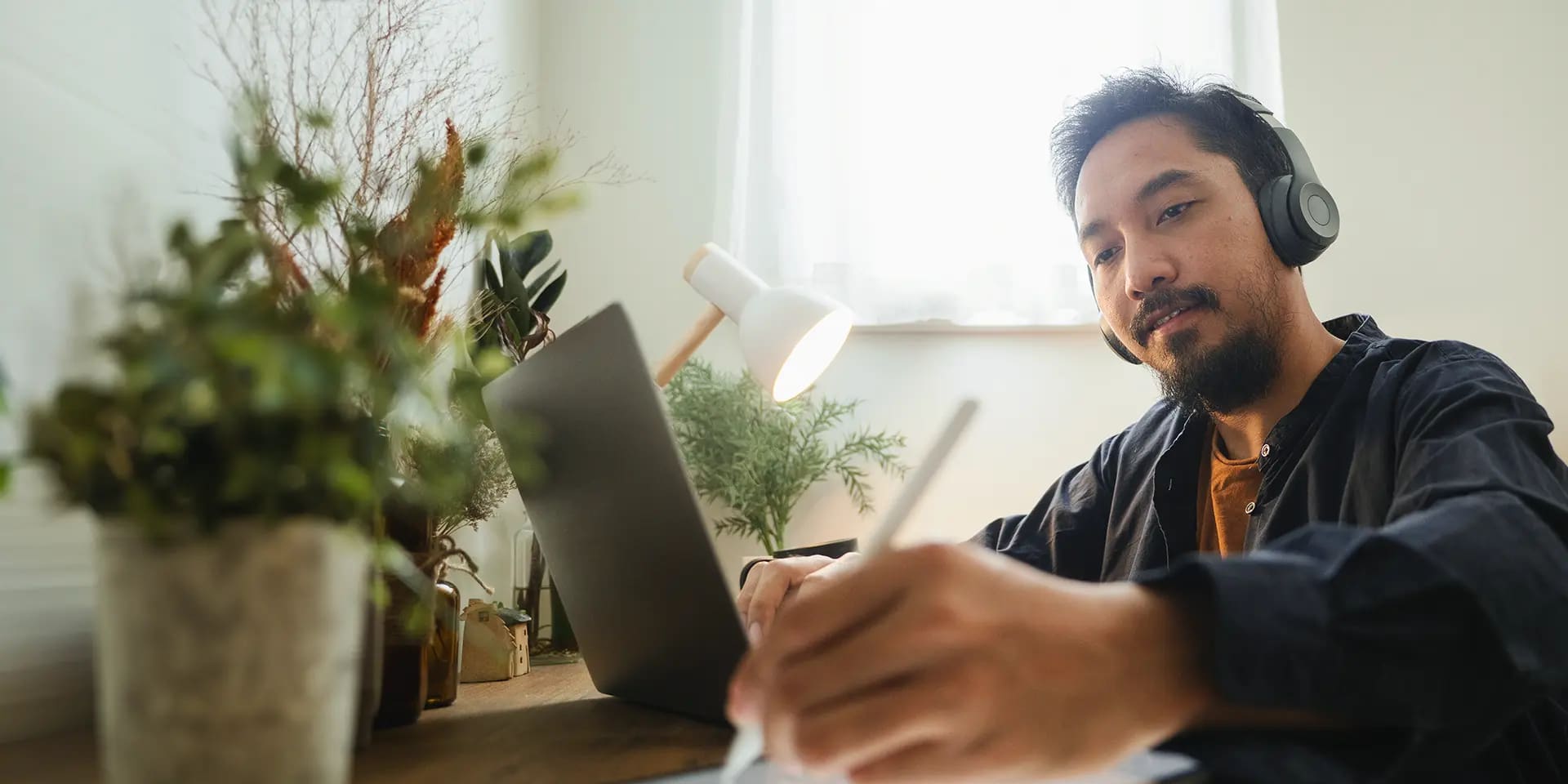Titelbild zum Artikel "Masterarbeit schreiben": Master-Student arbeitet am Laptop mit Kopfhörern