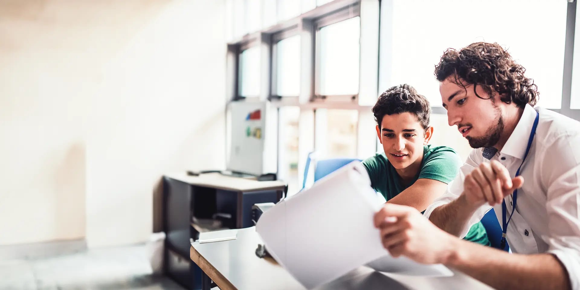 Titelbild zum Artikel "Beliebteste Studentenjobs": Student gibt einem Teenager Nachhilfe im Klassenzimmer