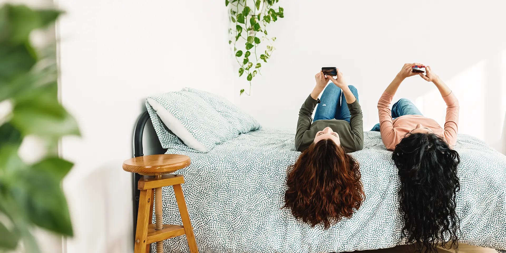 Titelbild zum Artikel "Handysucht überwinden": Zwei Freundinnen mit Handy liegen auf dem Bett