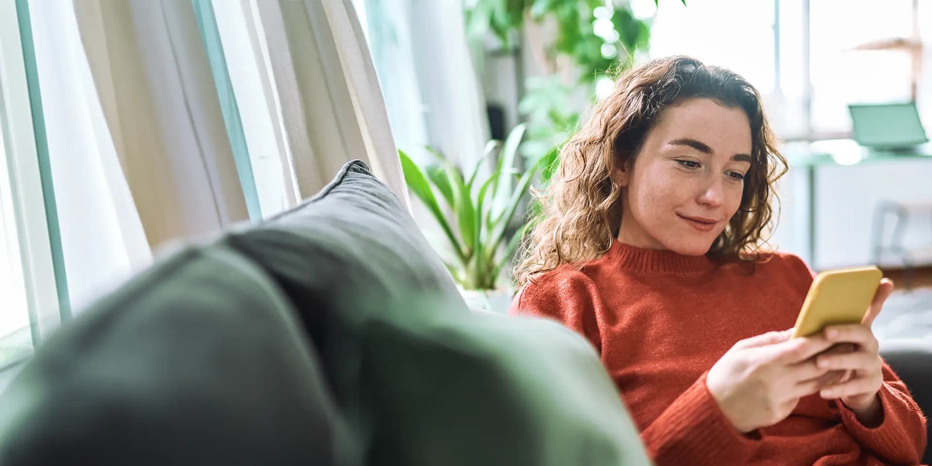 Titelbild zum Artikel "Was ist eine Customer Journey": Frau mit Handy sitzt auf dem Sofa