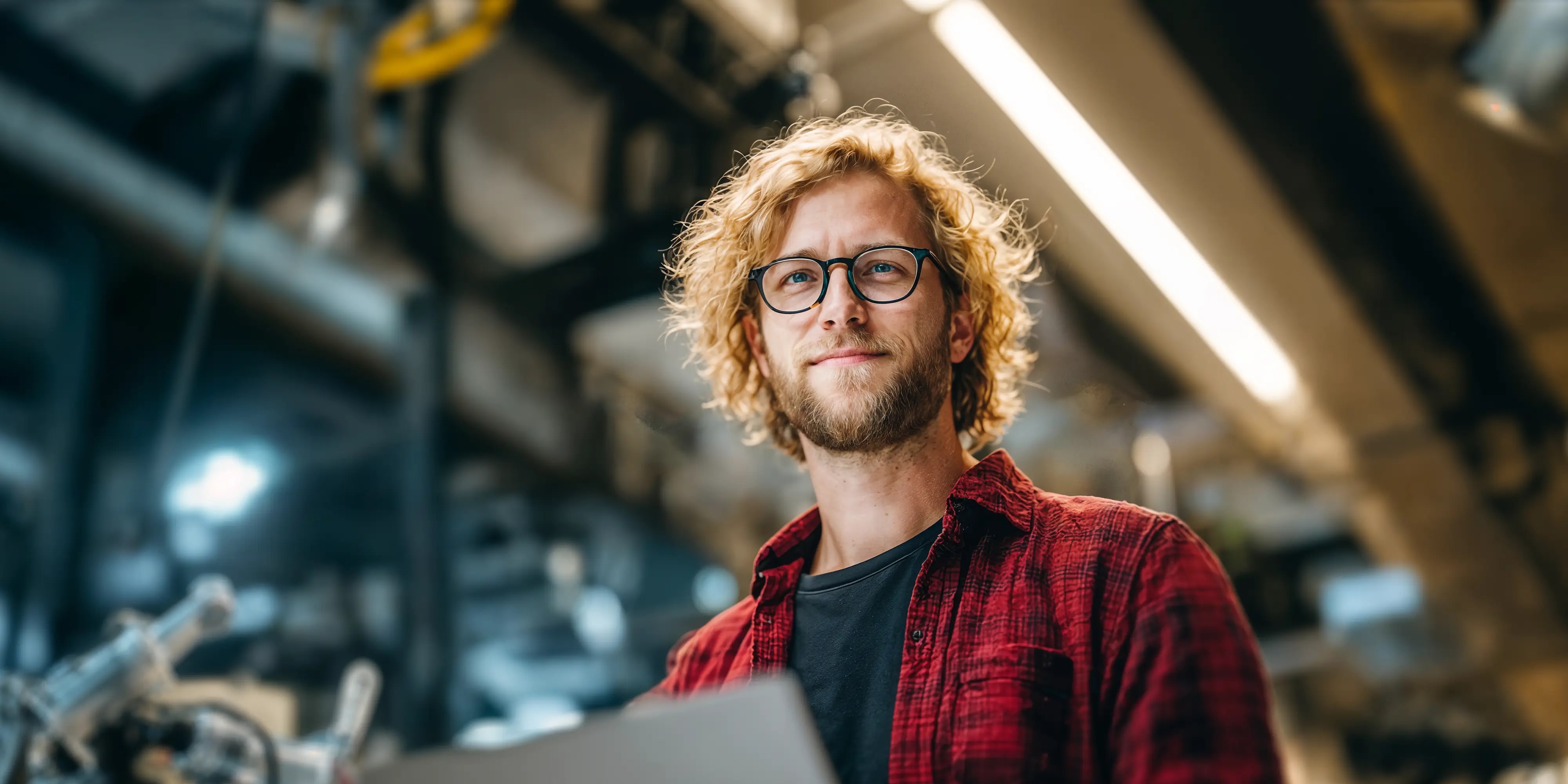 Bachelor Applied Artificial Intelligence: Mann steht mit Tablet in einer Werkshalle mit Robotik, AI-generated