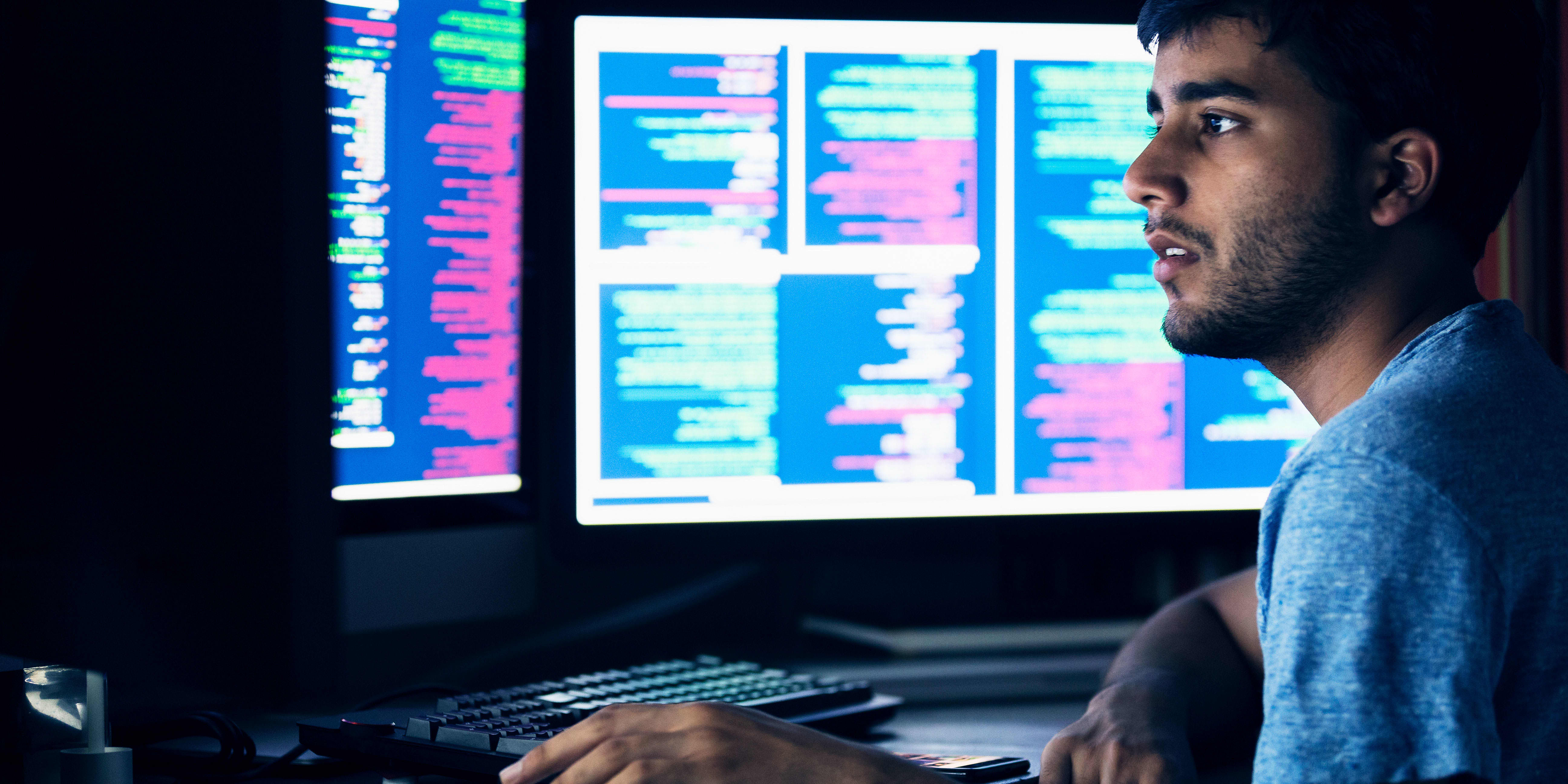 Man is sitting using a computer with different screens