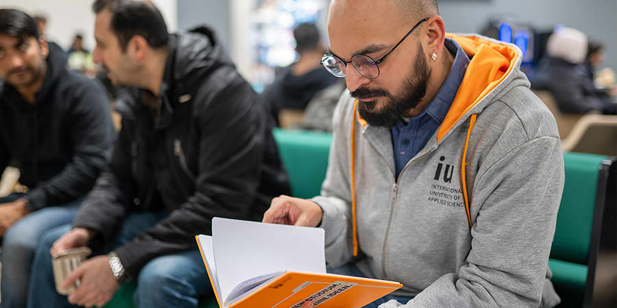 Student wearing glasses and a hoodie is reading through his bachelor's degree notes