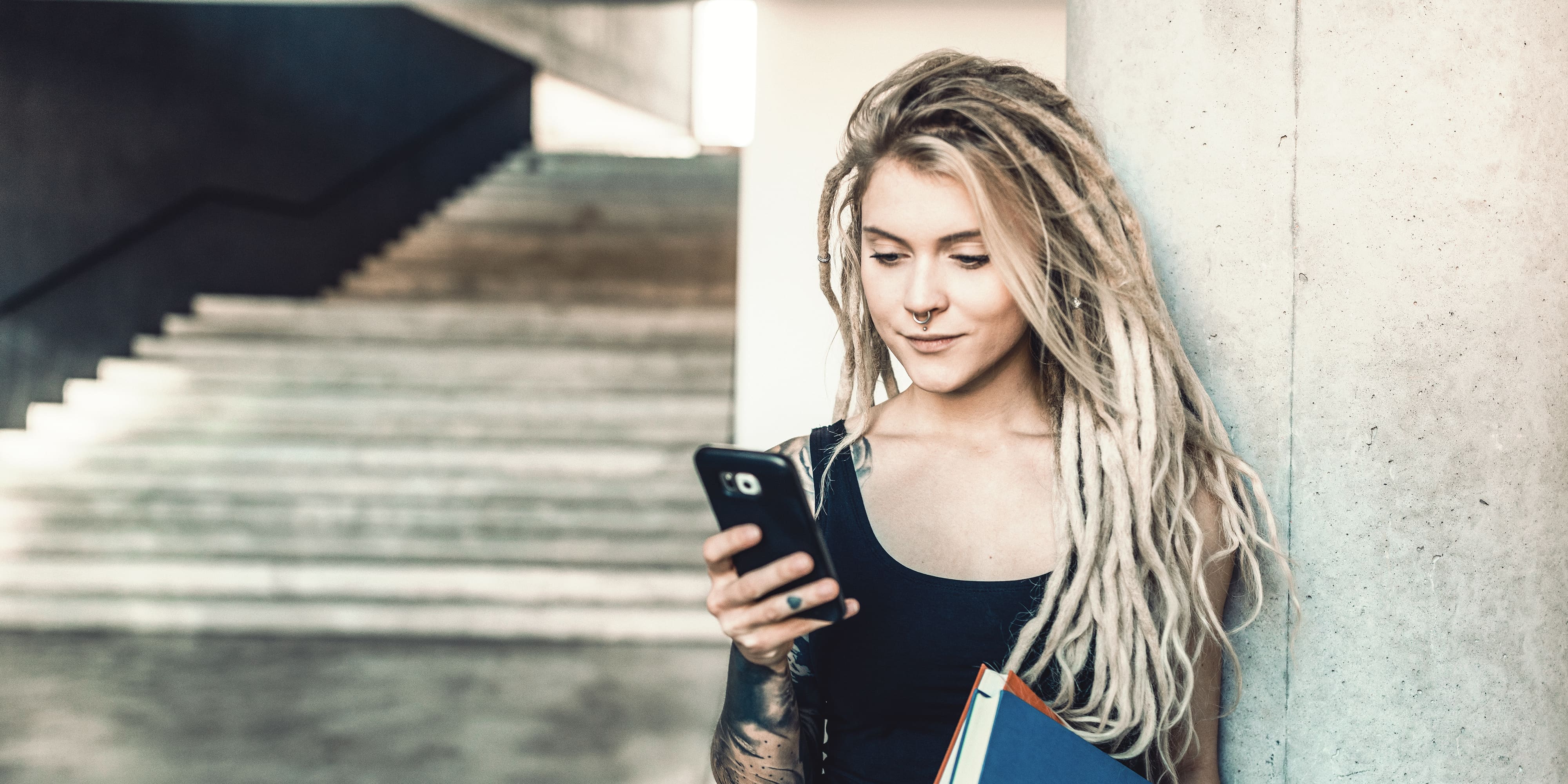 Titelbild für Artikel “Digital Detox”: Studentin informiert sich an ihrem Smartphone über die Möglichkeiten von Digital Detox