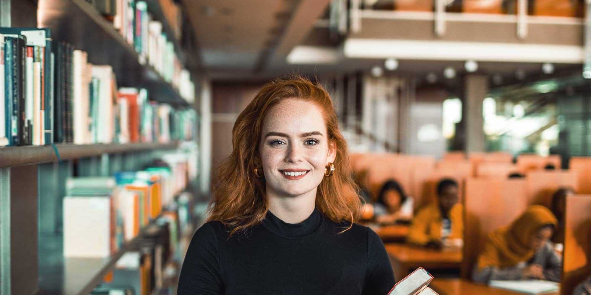 Studentin mit Büchern in der Hand in der Bibliothek