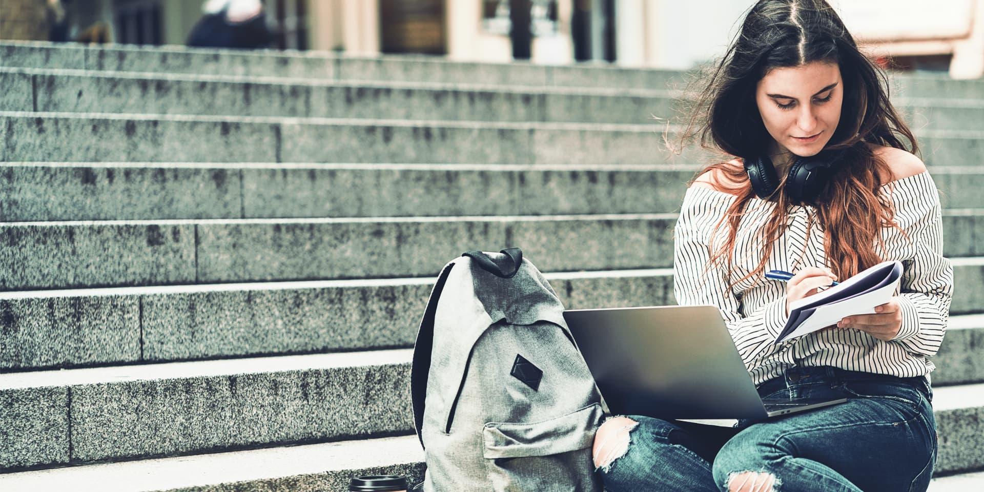 Studentin macht sich Notizen vor dem Campusgebäude