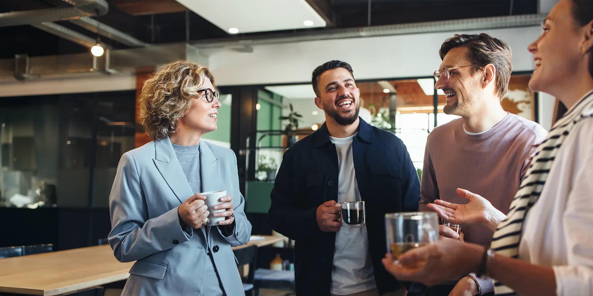 Titelbild zum Artikel "Networking Tipps": Gruppe Kollegen mit Tasse in der Hand unterhält sich