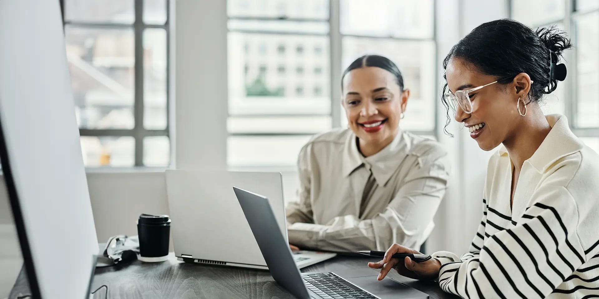 Titelbild zum Artikel "Was macht ein SEO Manger?": Zwei SEO Managerinnen arbeiten am Laptop