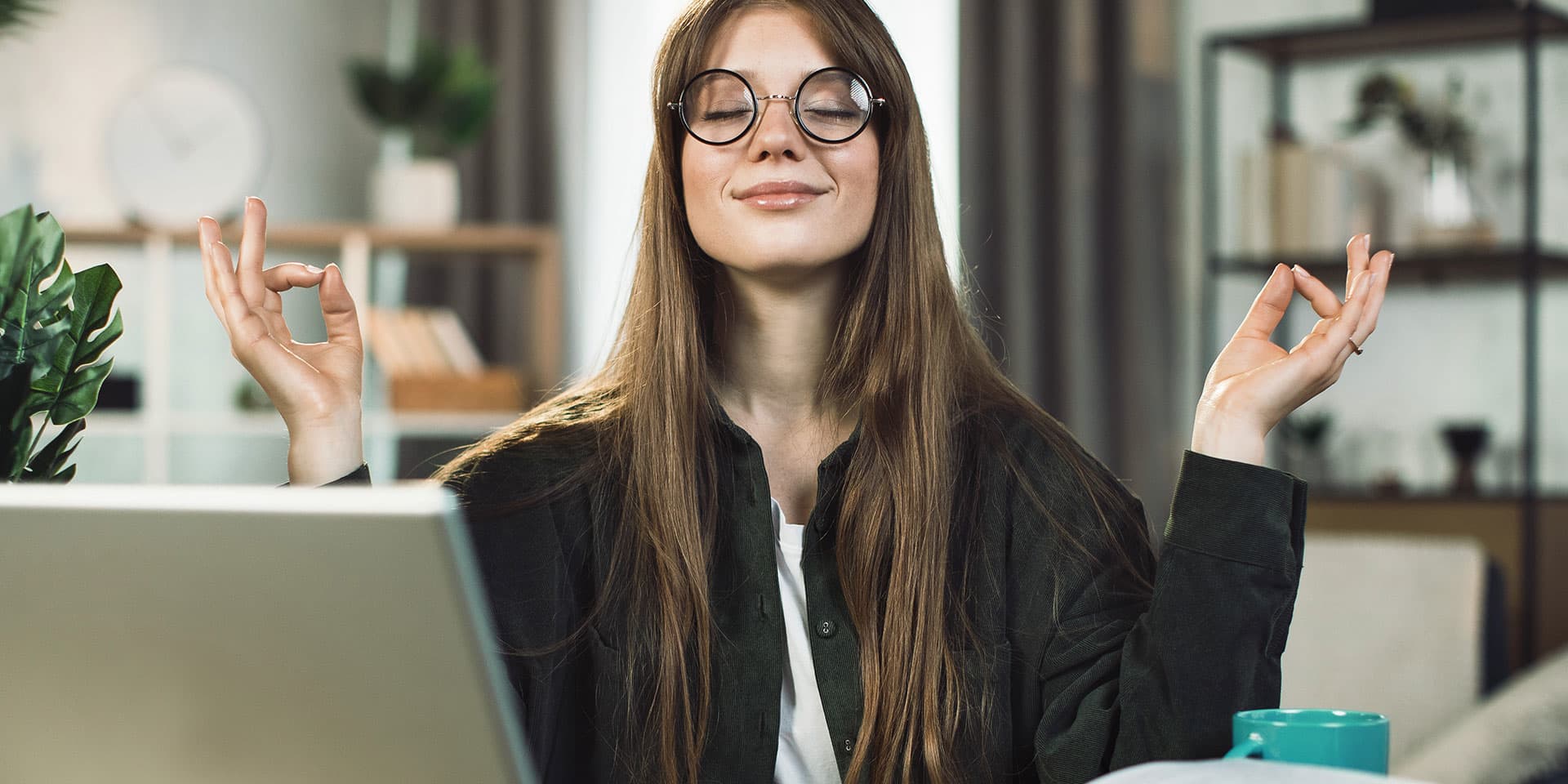 Titelbild für Artikel “Stressbewältigungsstrategien”: Studentin wendet eine Stressbewältigungsstrategie an und meditiert am Schreibtisch