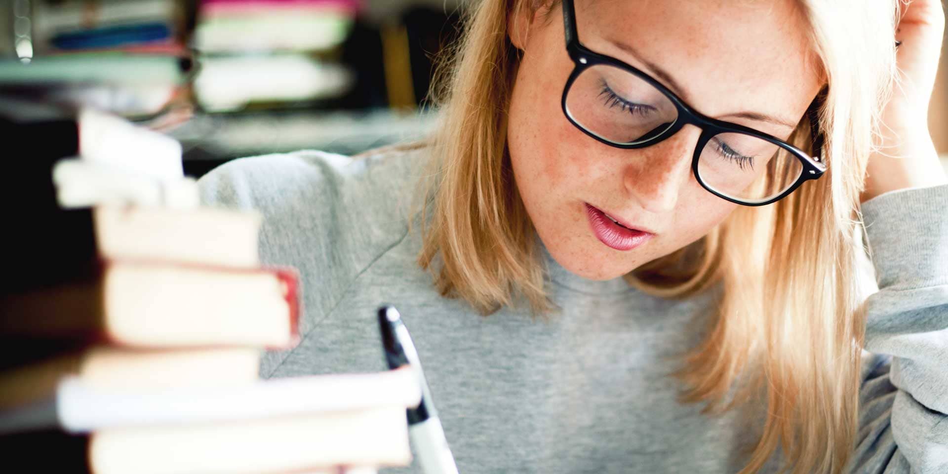 Junge Frau mit Büchern am Schreibtisch