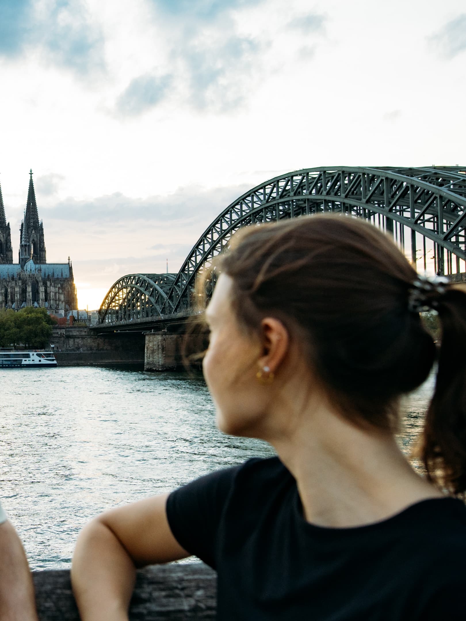 Two IU students looking at the Cologne skyline with Cologne Cathedral and the Hohenzollern Bridge across the Rhine River.