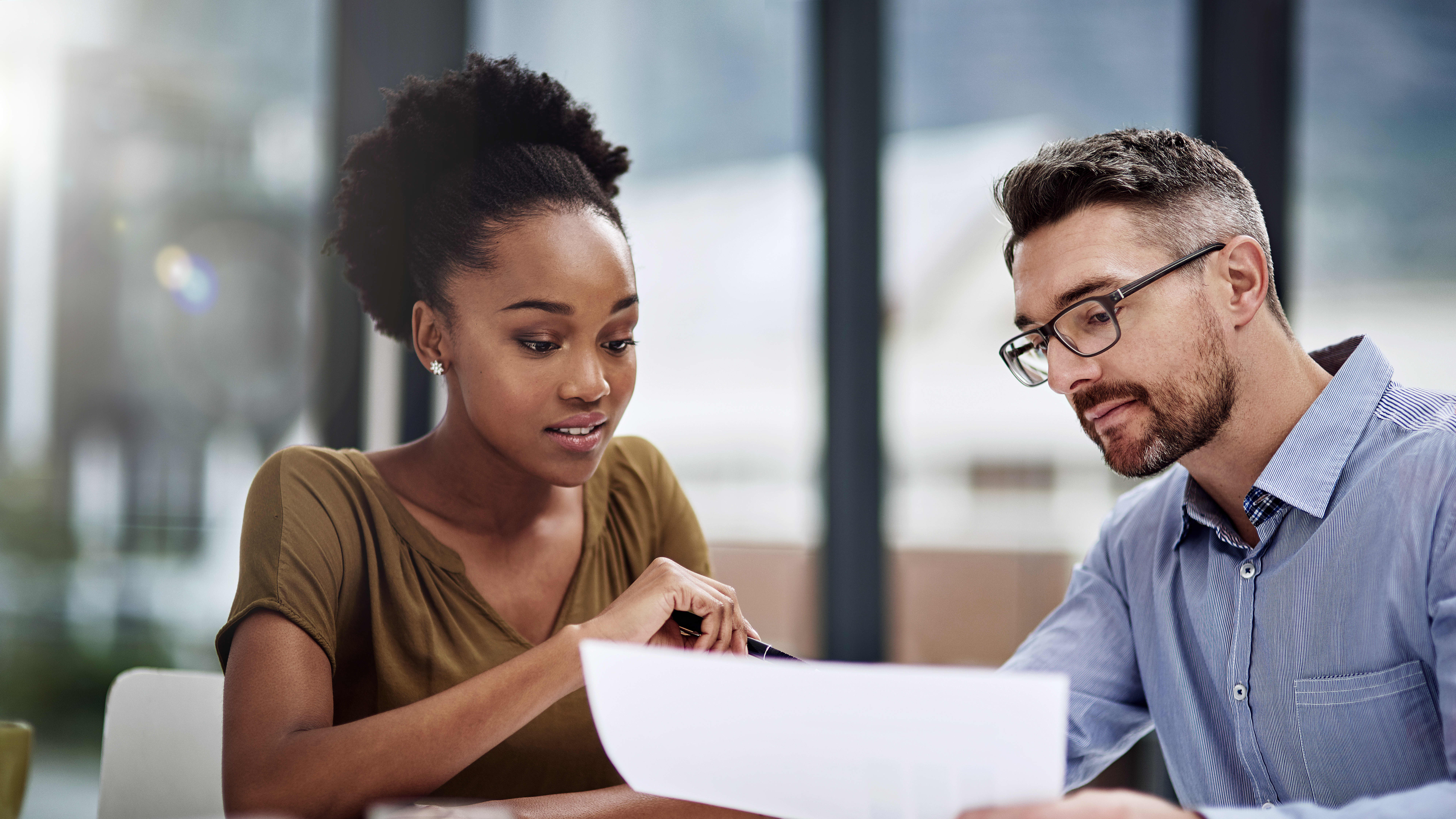 Two mba students looking over a sheet of paper that highlights the analytical skills, entrepreneurial skills and communication skills they can gain in their program.