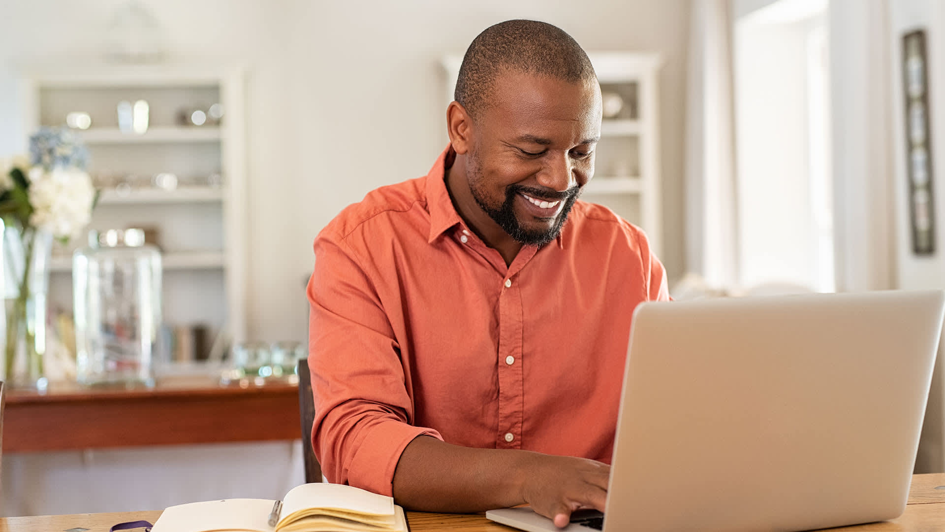 A man sitting at his desk with his computer and smiling.