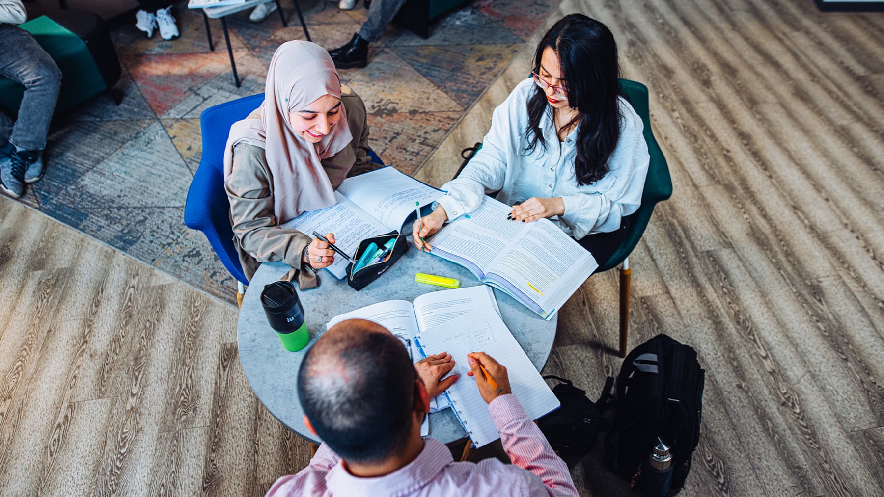 Smiling international students study for their computer science programme together around a table