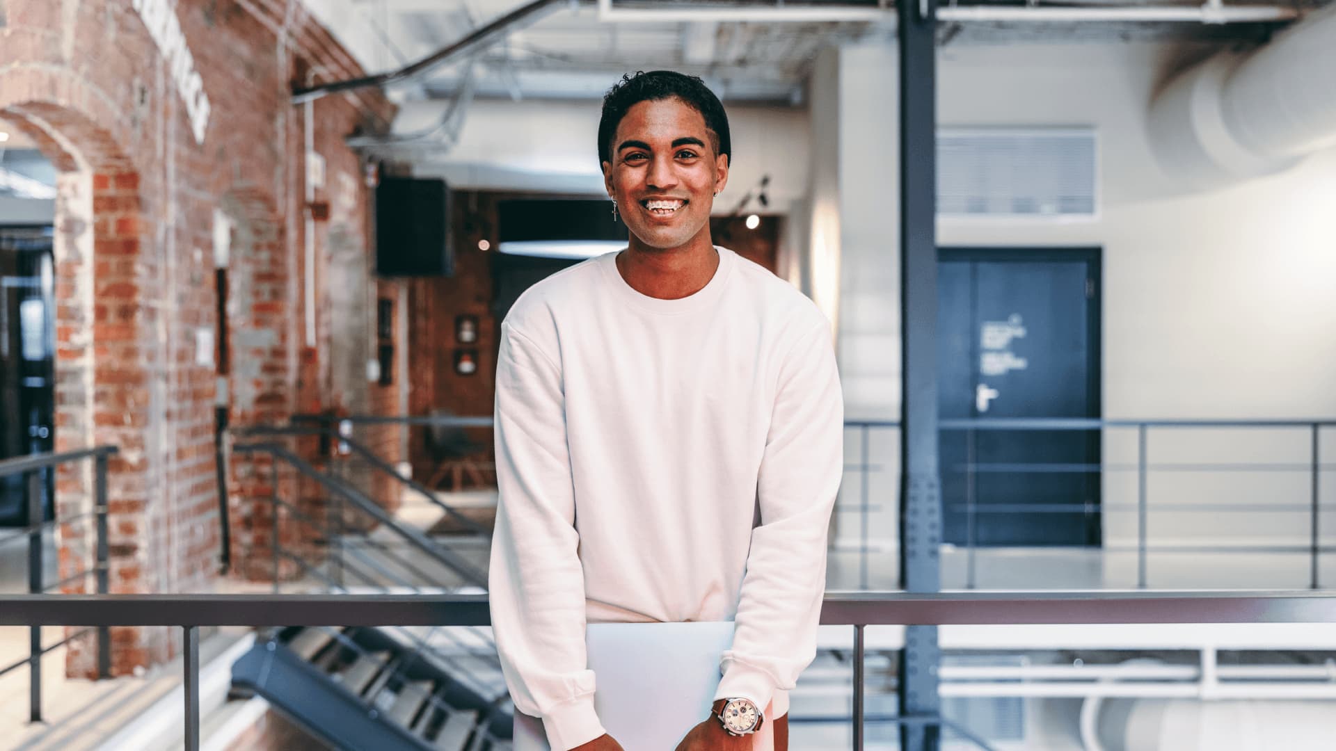 Data degree student holding laptop in a modern office.