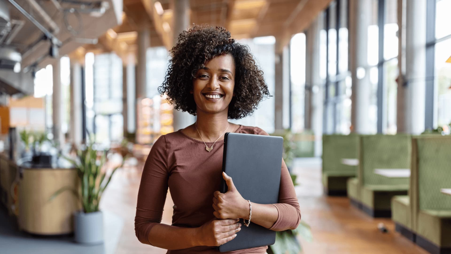 Female data scientist holding laptop in modern office.