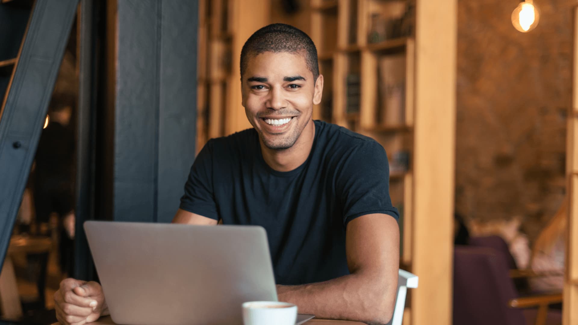 Smiling man in café looking for online degrees on the subject of banking and finance.