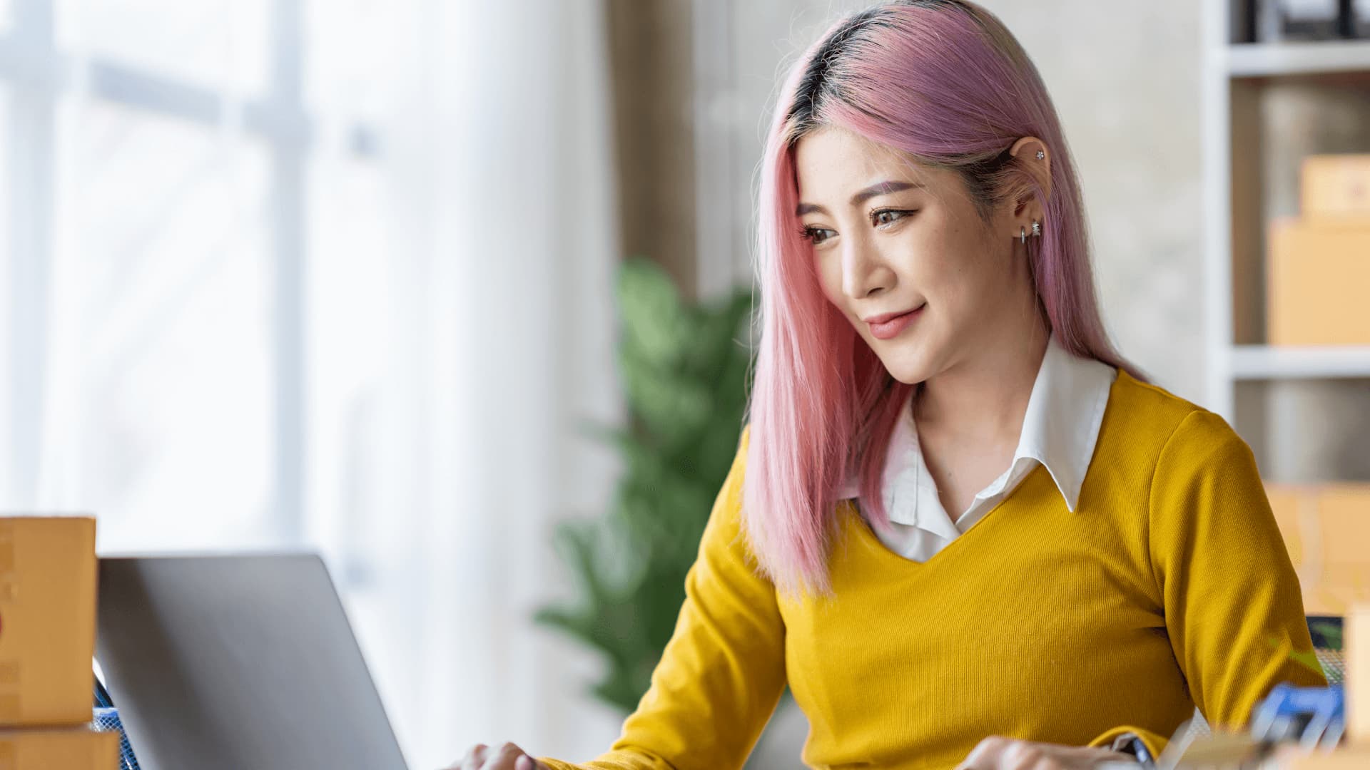 Woman with pink hair studying data management degree course from home.