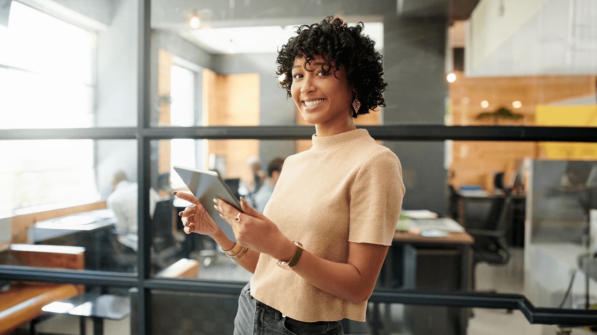 Happy woman in brown t shirt holding an ipad exploring business management careers.