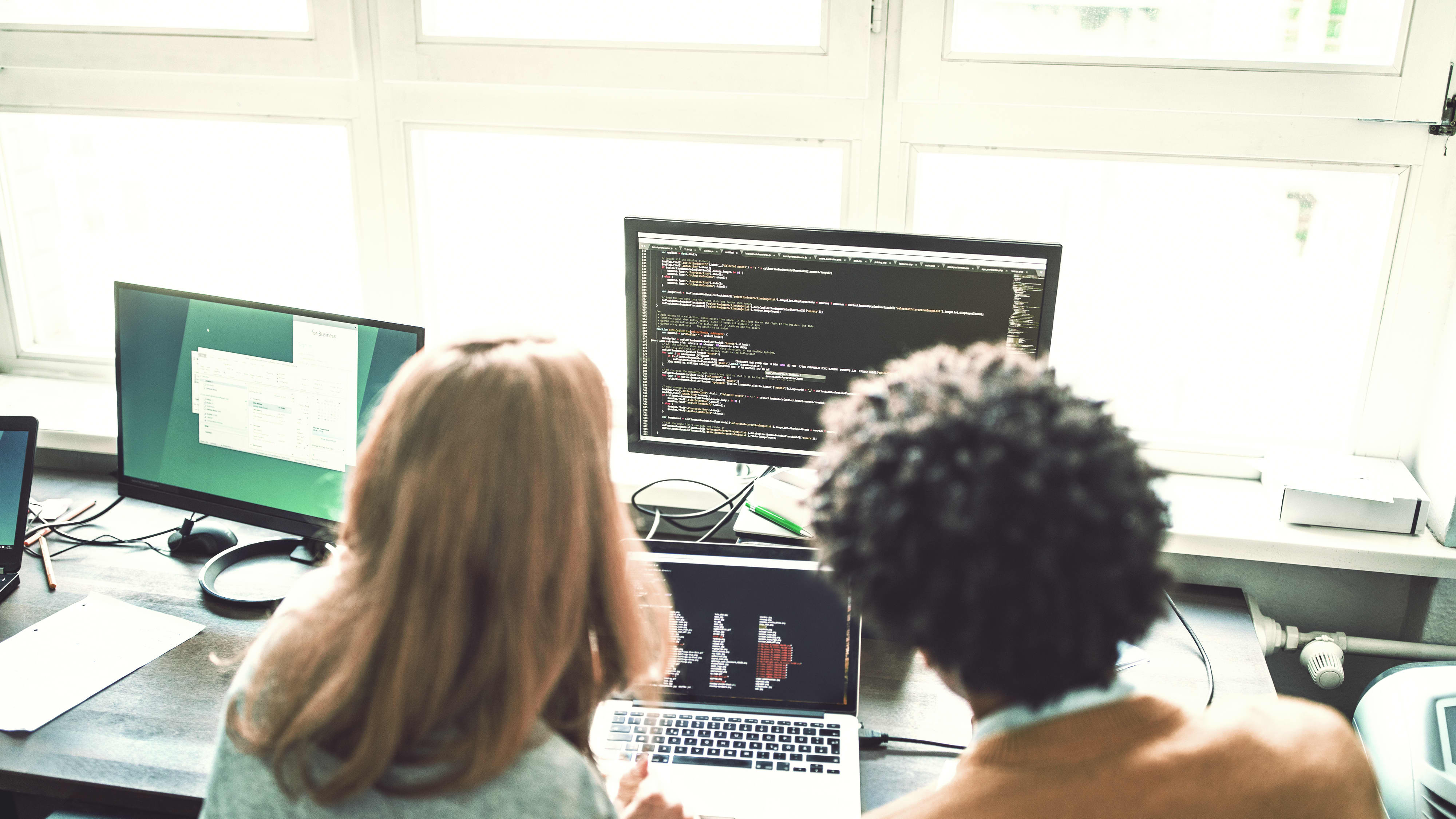 Back view of two computer scientist working with data sets