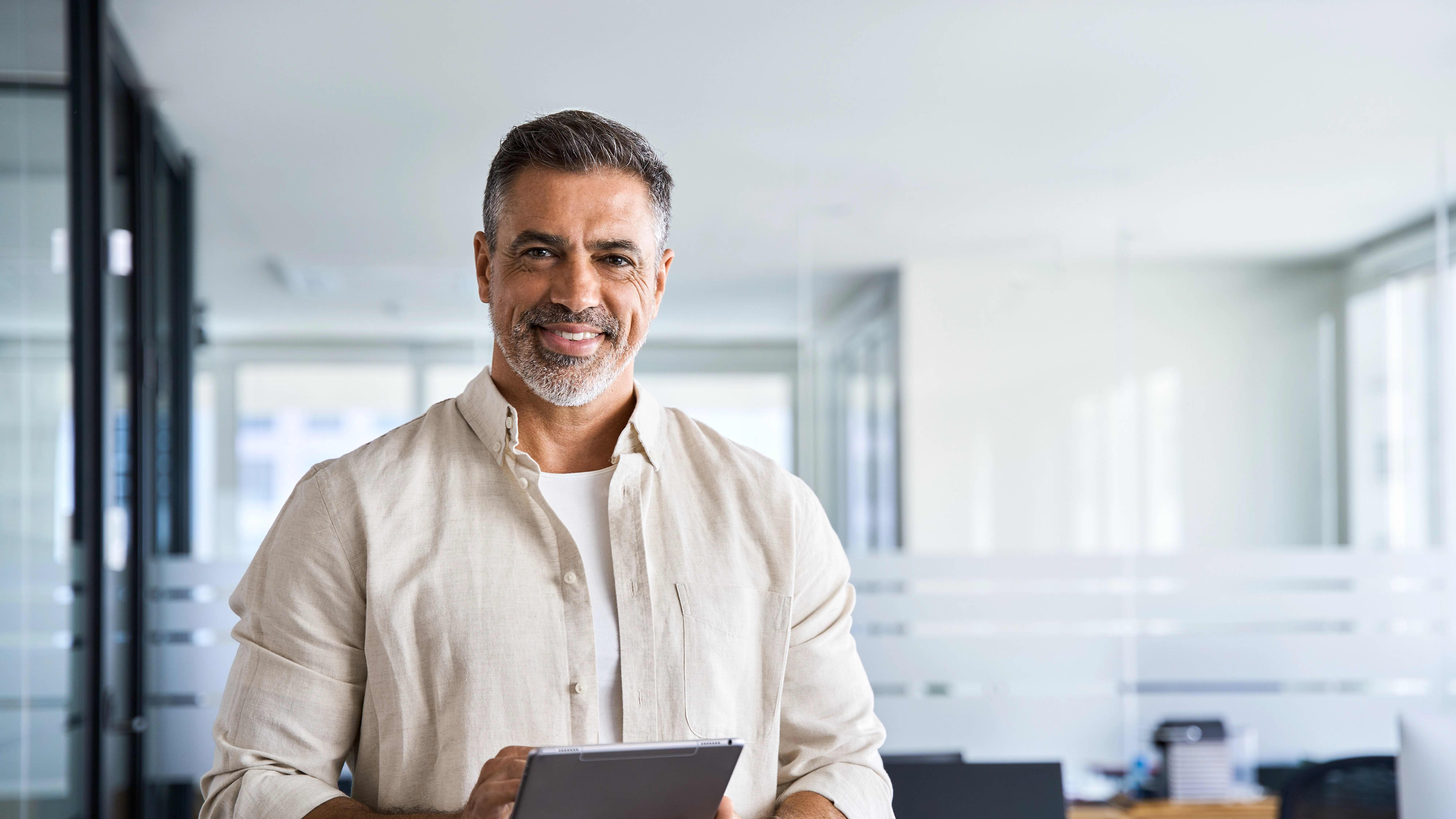 Adult man holding a tablet and smiling in an office environment