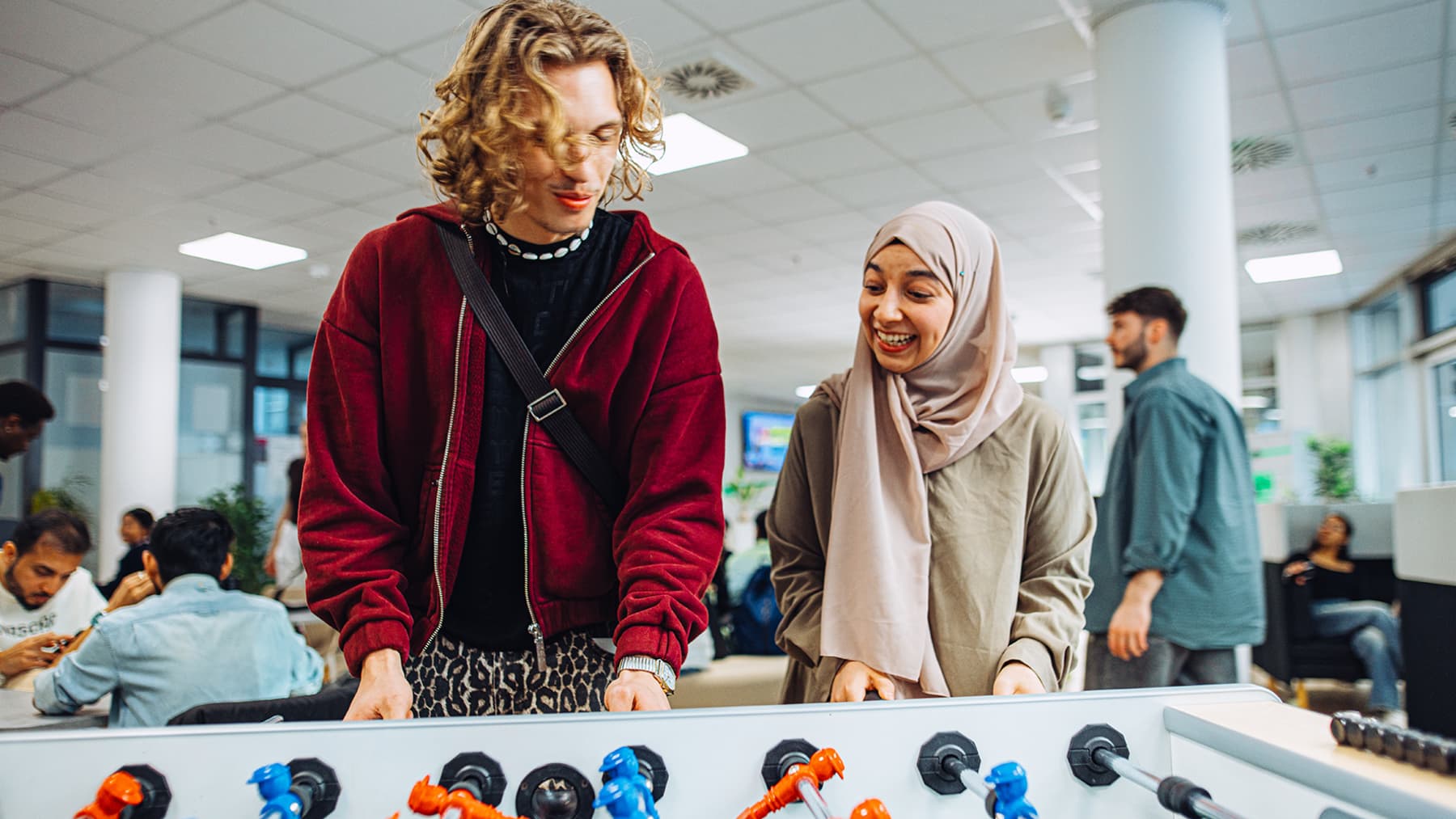Two students play table football in a university common area