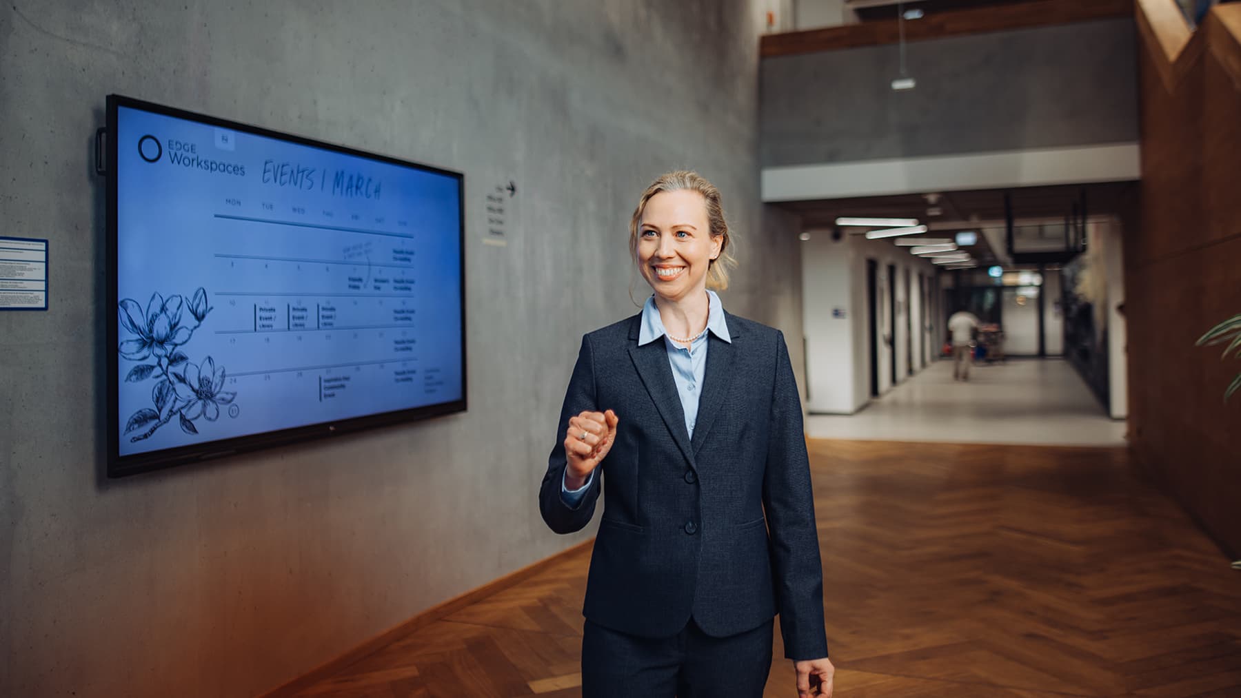 A professional student walks through the corridor of a modern university building next to an events schedule