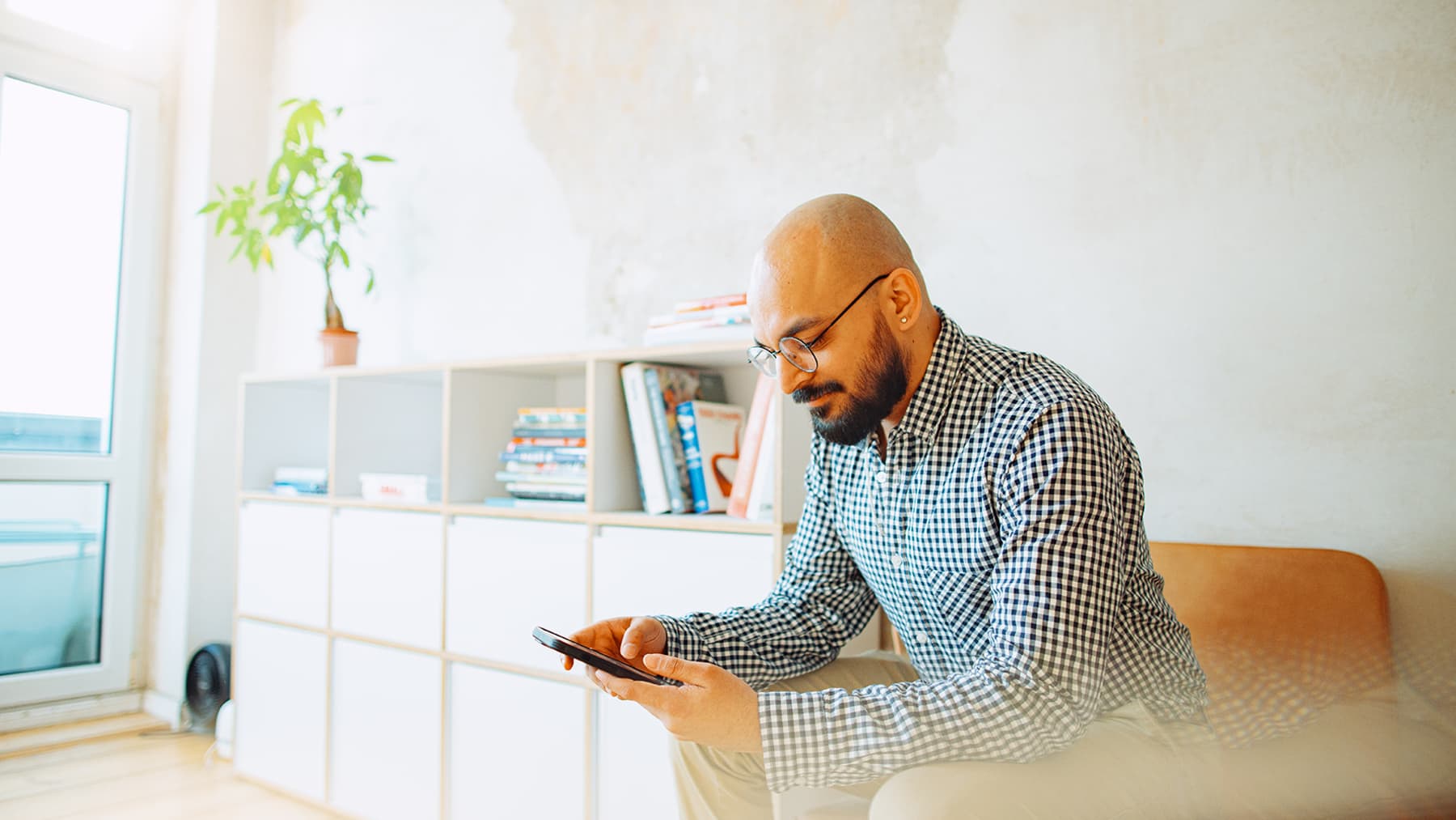 A student looks at his phone while sat in a modern room