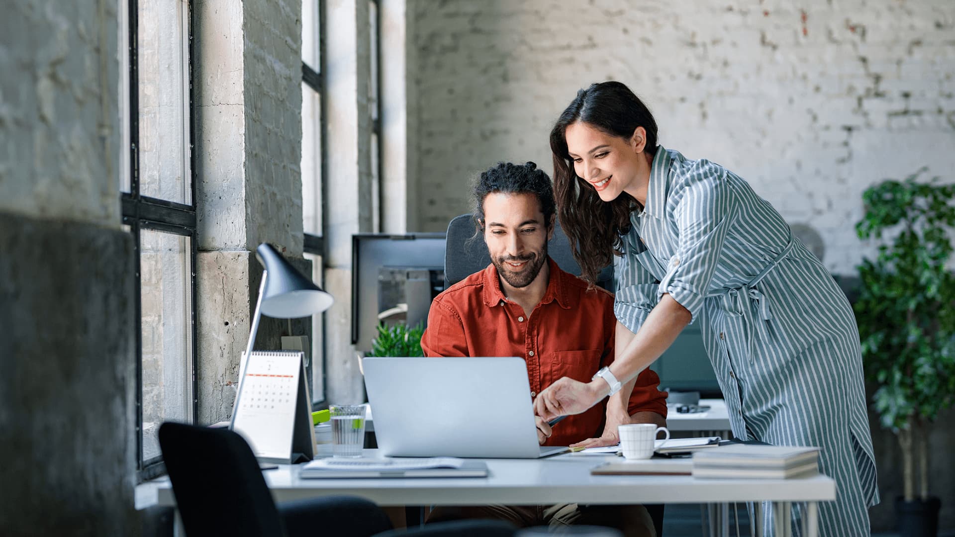 Colleagues sitting in a modern office are pointing at their desktop are discussing how to manage suppliers and ensure timely delivery of goods