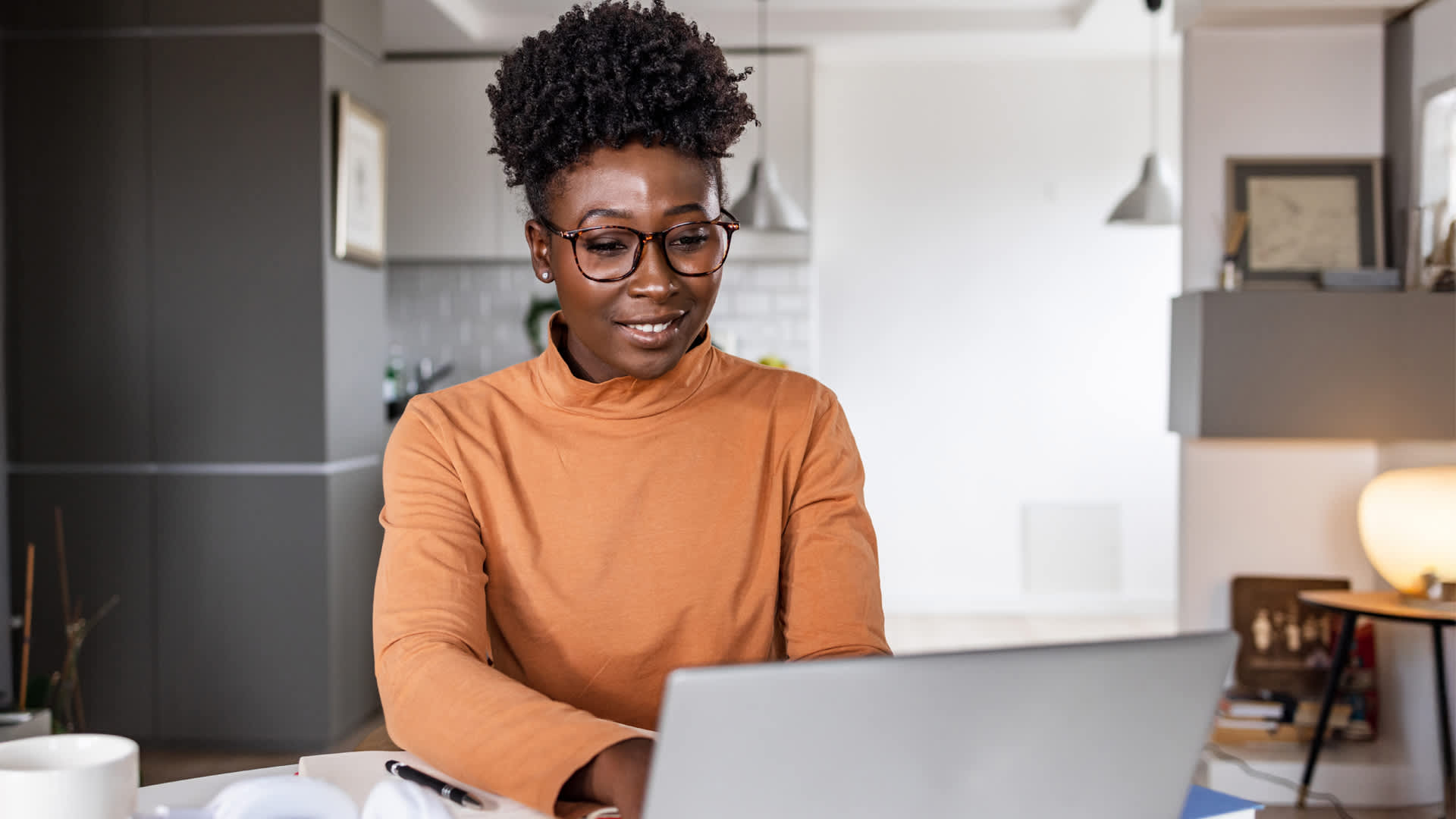 Woman in glasses and orange top exploring entry requirements for both a master and management degrees