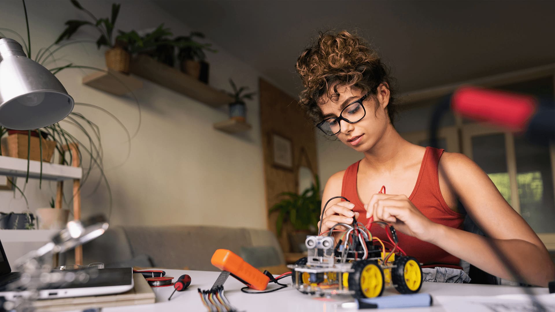 Curly hair woman wearing glasses is working in the architectures of autonomous vehicles in her small office