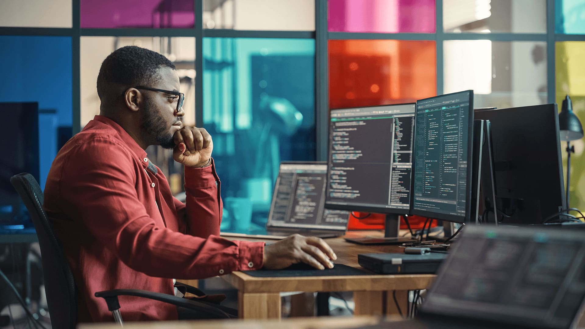 Man sitting in front of his desktops working on projects involving image and speech recognition