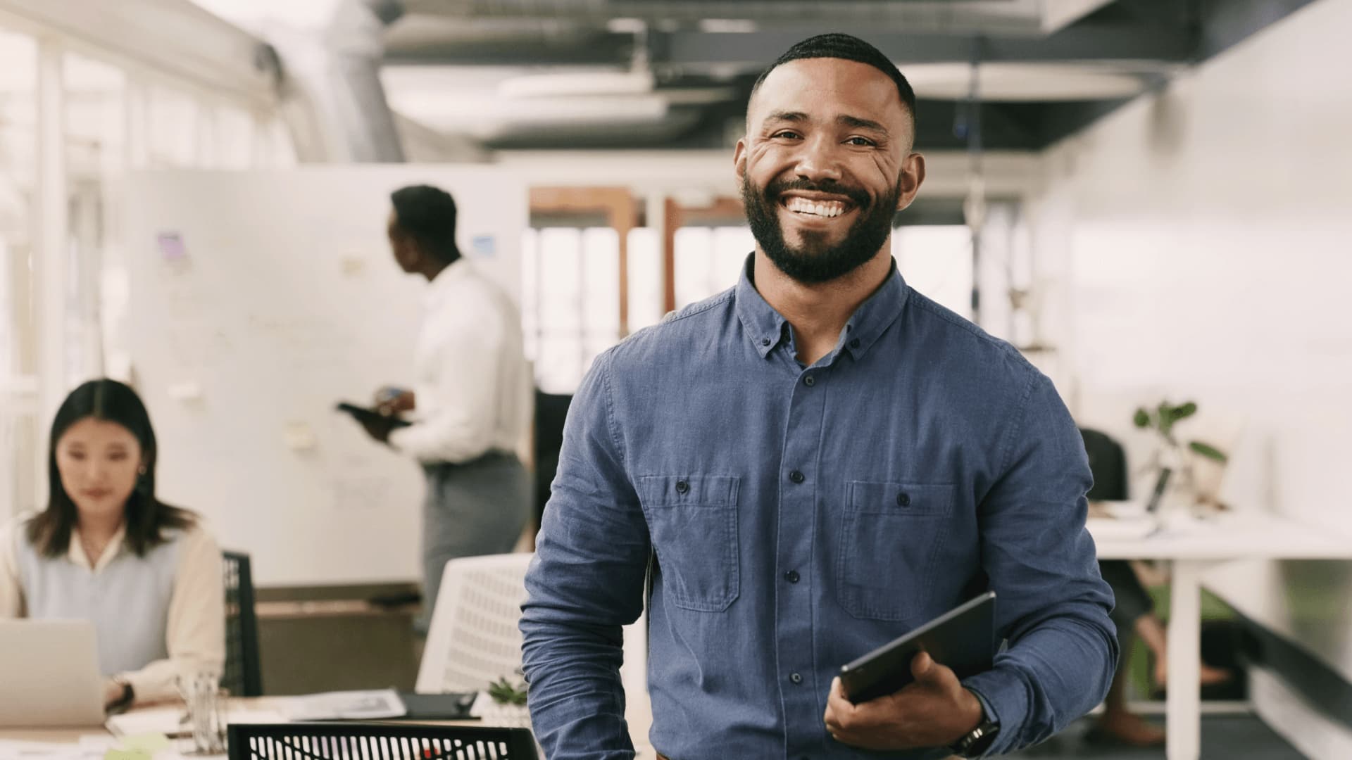 Male business manager in navy shirt smiling in office of operations managers.